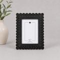 Black scalloped wood picture frame holding a 5x7 photo, side detail view