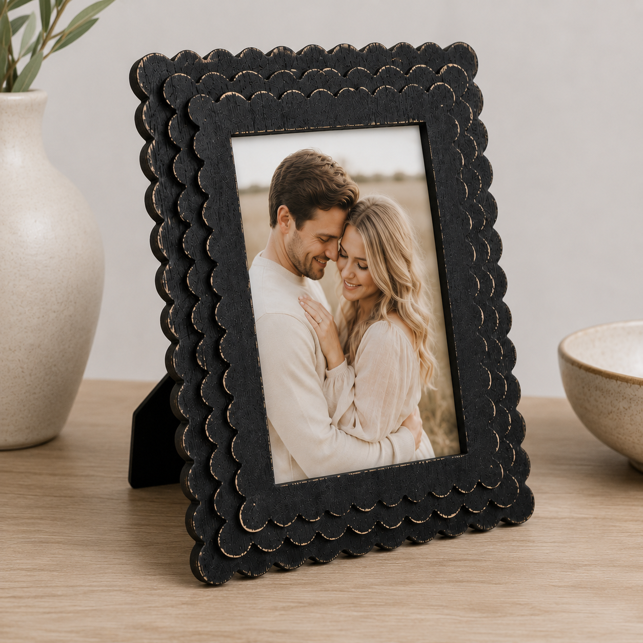 Black scalloped wood picture frame holding a 5x7 photo, angled view