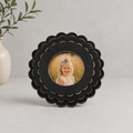 Black round scalloped wood picture frame holding a 4x4 photo, side detail view