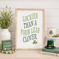 wood framed wall art featuring luckier than a four leaf clover displayed in a styled home interior.